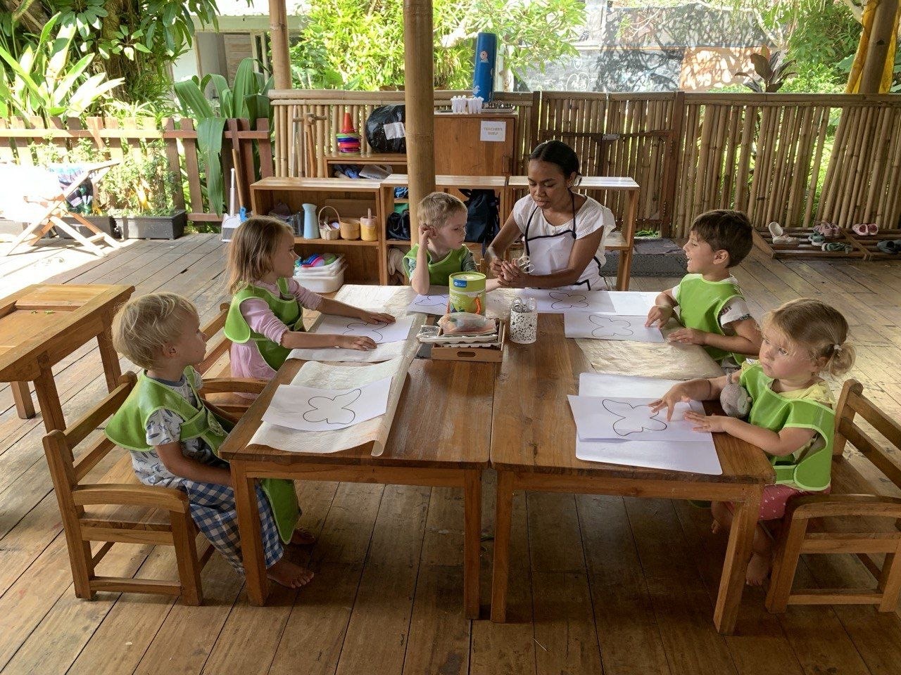Children and their teacher working together in the open bamboo pavilion at Balu Kids near Ubud, Bali