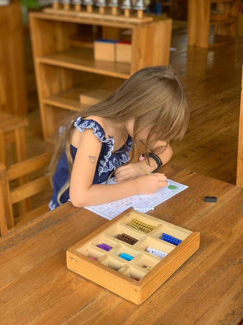 Child working with Montessori bead material at a desk