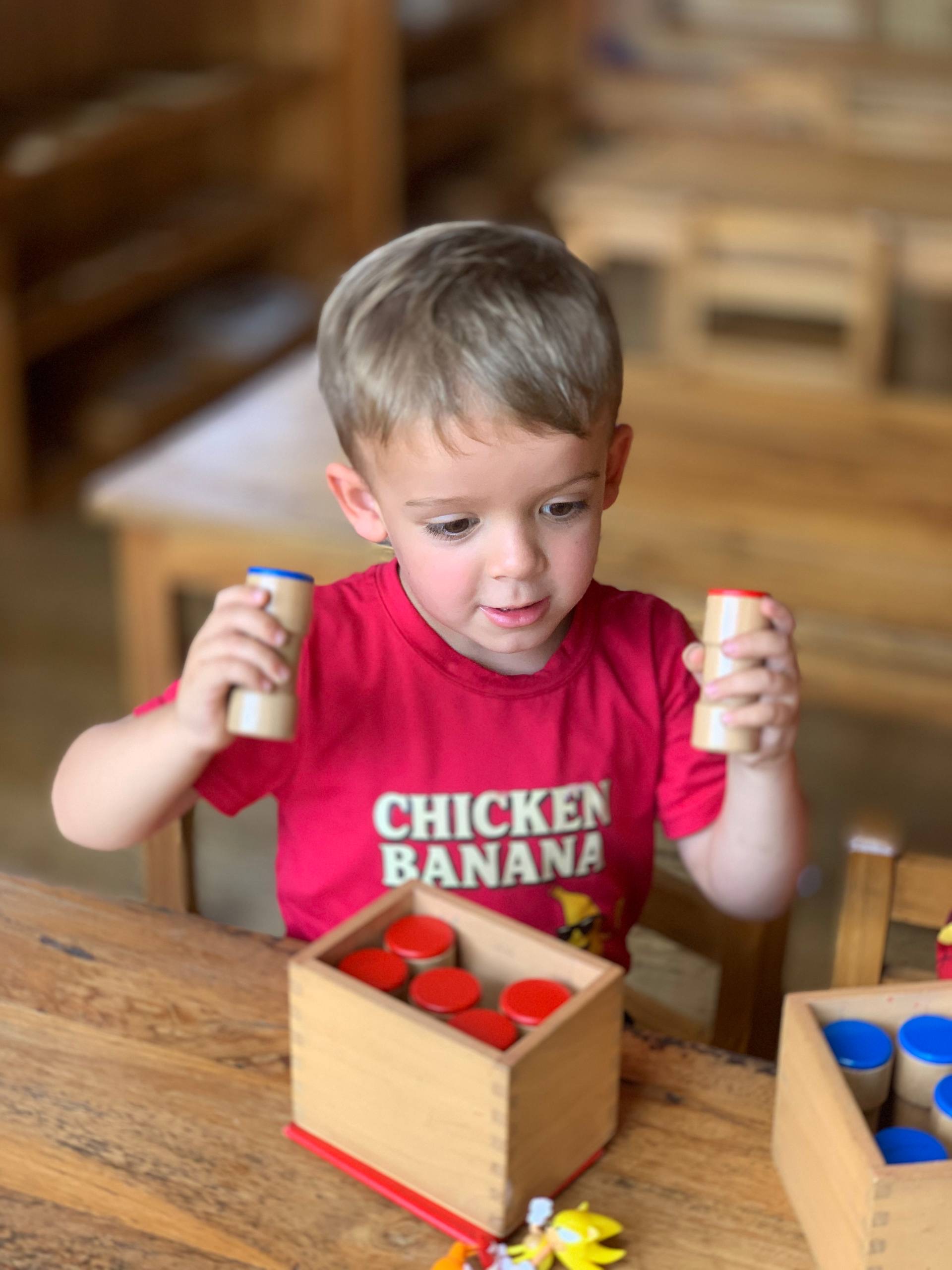 A young child sorting wooden cylinder blocks at Balu Kids near Ubud